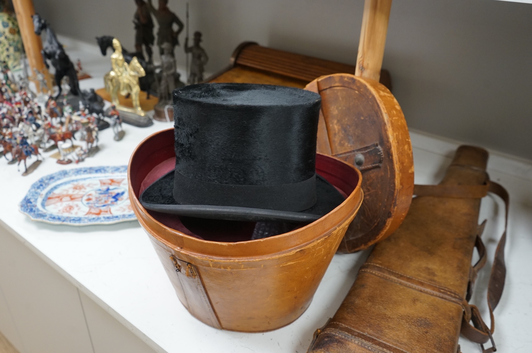 A 'Leg of Mutton' leather gun case and a top hat in leather case, gun case 75cm long.